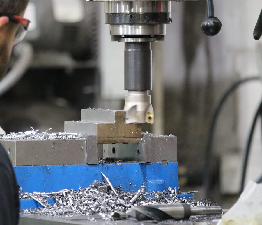 A worker cutting down a piece of metal